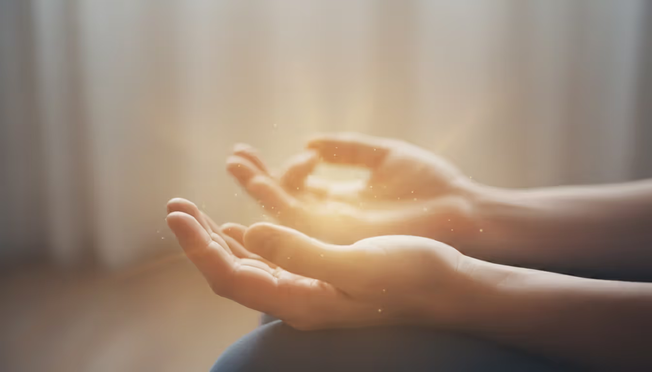Close-up of relaxed hands resting palms up on knees during meditation with warm soft light around them