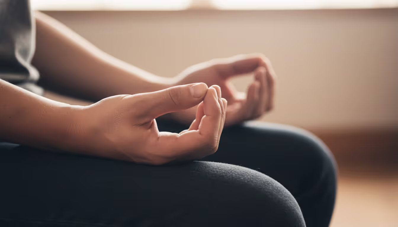 Close-up of hands forming the cosmic mudra (hokkai-join) during zazen meditation with softly blurred warm background
